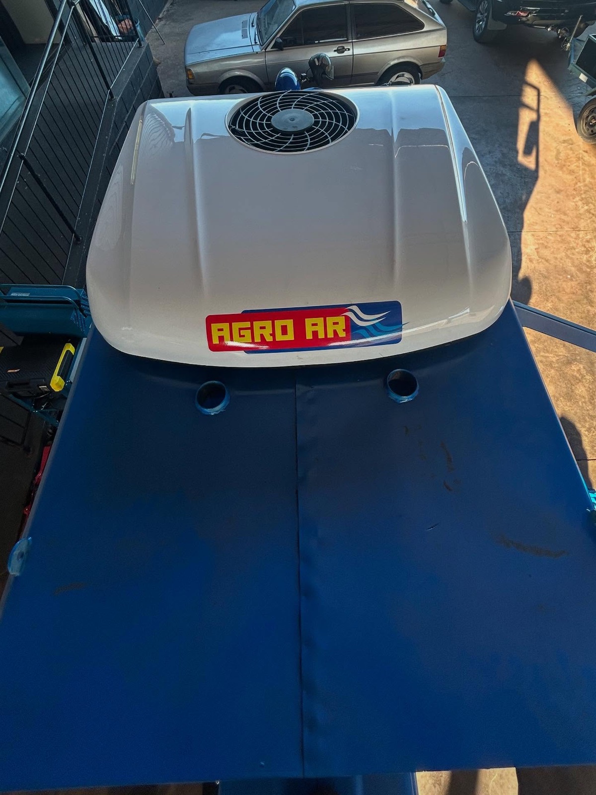Unidade de ar elétrico com adesivo Agro AR no teto do trator